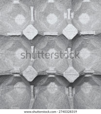 Close up of an empty recycled paper egg carton tray with repetitive geometric pattern and soft shadows.