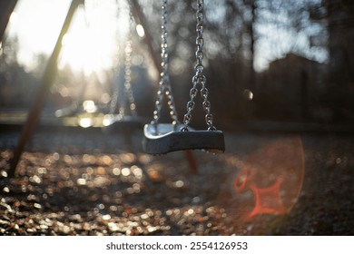 close up of empty swing. sunlight on background.