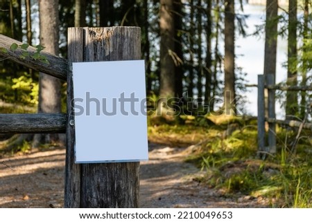 Close up of empty white sign on a wooden fence post in the woods
