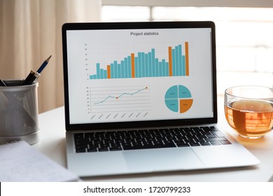 Close up of empty workplace with open laptop with financial project statistics graph, modern computer gadget with finance diagram, online study course or training, freelance work, education concept