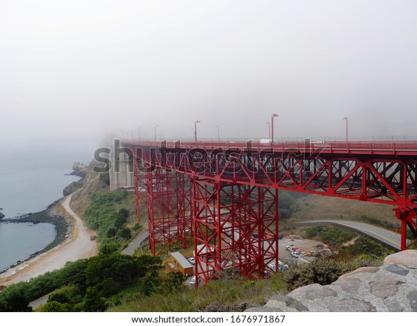 Close up of the end part of the Golden Gate\
Bridge made invisible by a thick fog.\
