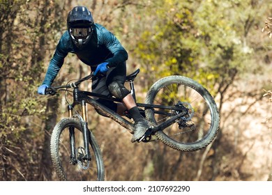 Close Up Of Enduro Mtb Rider Jumping Down The Mtb Track By Bikepark In The Mountains Of The Pyrenees In Catalonia. With Full Face Helmet, Goggles, Cycling Gear And Winter Protections.