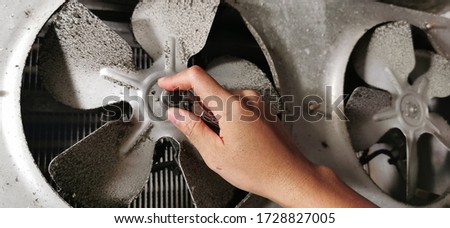 close up The Engineer hand holding a screwdriver to remove the dirty fan blades of walk-in chiller for deep cleaning at restaurant for good hygienist