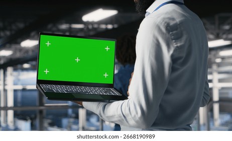 Close up of engineer on data center industrial platform analyzing performance outputs on green screen laptop. Server room IT expert finetuning server rig configurations using mockup notebook