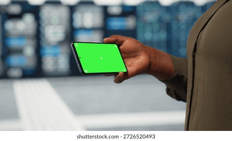 Close up of engineer using app on mockup phone to check server farm energy consumption. System administrator using green screen smartphone in data center to do infrastructure checkup