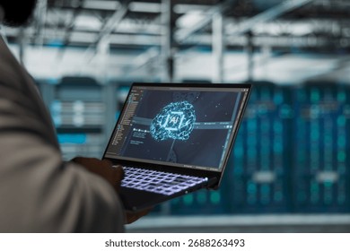 Close up of engineer using laptop in data center housing advanced equipment used for complex AI calculations. Server room IT professional running artificial intelligence code to optimize performance