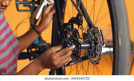 Close up of engineer using screwdriver and hex socket wrench to secure wheel on bicycle in studio background. Professional screwing bolts on bike parts, mending rear derailleur and cassette, camera A - Powered by Shutterstock