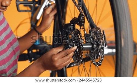 Close up of engineer using screwdriver and hex socket wrench to secure wheel on bicycle in studio background. Professional screwing bolts on bike parts, mending rear derailleur and cassette, camera A