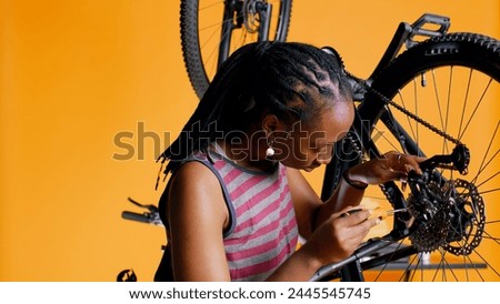 Close up of engineer using screwdriver and hex socket wrench to secure wheel on bicycle in studio background. Professional screwing bolts on bike parts, mending rear derailleur and cassette, camera B