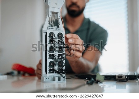 Close up of engineer's hands building and programming a robotic hand at home.