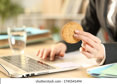 Close up of entrepreneur woman hands holding cookie working on laptop at home office - Powered by Shutterstock