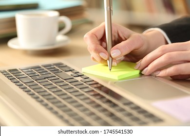 Close up of entrepreneur woman hands writing reminder on post note on a desk at home