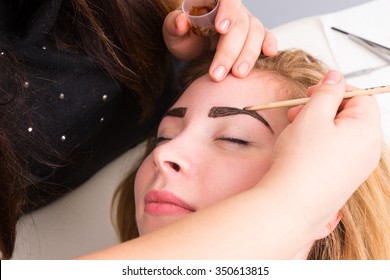 Close Up Of Esthetician Filling In Eyebrows Of Female Client With Dark Brown Make Up During Eyebrow Spa Treatment - Blond Client Looks Contented And Relaxed