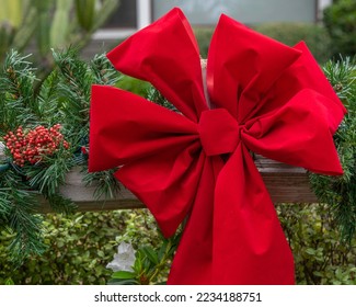 Close up of an evergreen Christmas wreath with a red ribbon hangs on a fence post. - Powered by Shutterstock
