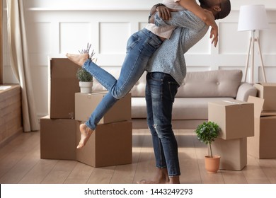 Close up of excited african American man husband lift wife kiss in living room feel overjoyed on moving day, young happy couple stand near cardboard boxes show love relocating to new house together - Shutterstock ID 1443249293