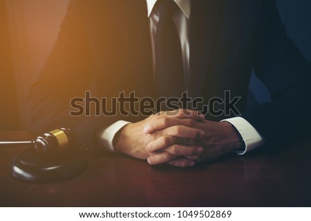 Close Up Executive Lawyer or JUDGE hand Striking the GAVEL on Sounding Block in LAW Office, 
 JUSTICE and LAW Concept Background,  Businessmen in Suits Sitting on the Table Next to a ็Ammer.