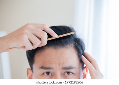 Close Up Of Exhausted Asian Man Brush His Hair With Comb