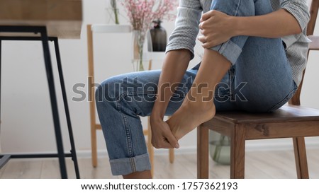 Close up of exhausted businesswoman touch massage foot suffer from uncomfortable heels shoes at work, tired unwell female feel discomfort in legs, relieve pain from feet ache, have strained muscle
