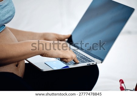 Close up of expecting mother using laptop and credit card for secure online shopping and digital payment during pregnancy at home