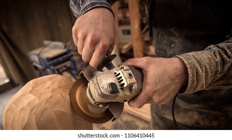 Close up of an experienced carpenter in work clothes and small buiness owner working in woodwork workshop, processes the board with an angle grinder on the table is a hammer and many tools  - Powered by Shutterstock