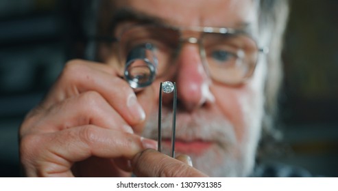 Close up of experienced goldsmith controlling a quality of diamond stone, selected for making jewels in workshop. Concept of jewelry,luxury,goldsmith, diamonds, brilliance.