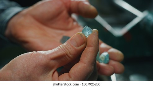 Close up of experienced goldsmith sorting high quality aquamarine stones, selecting them to make precious jewels in workshop. Concept of jewelry, luxury, goldsmith, diamonds,brilliance