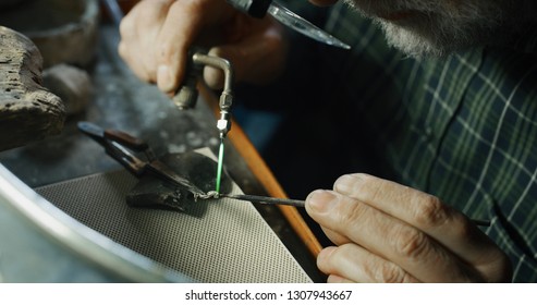 Close up of experienced goldsmith working on a handmade jewelry bracelet chain of precious metal white gold in a workshop. Concept of jewelry, luxury, goldsmith, gold, silver, precious metals