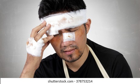 Close up expression of a man with bruised and bandaged face feels traumatic head pain. Conceptual image of accident victim healthcare