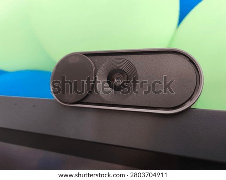 Close up of external black webcam with slide privacy cover mounted on laptop screen, macro view of computer web camera lens for online meeting, video calling, and digital security devic
