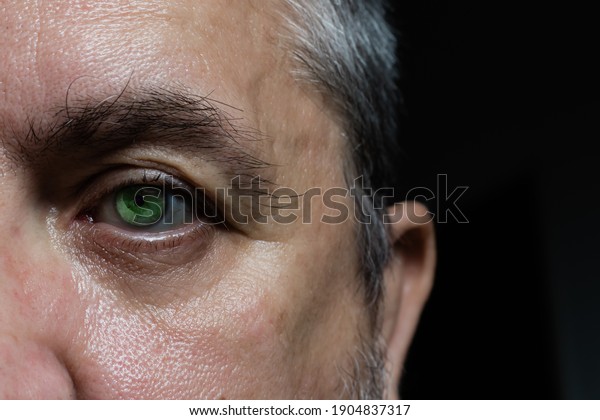 close up of an eye and right side of a man\'s\
face. black background