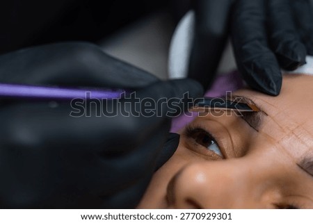 Close up of eyebrow shaping and mapping before permanent makeup, beautician marking brow symmetry in beauty salon
