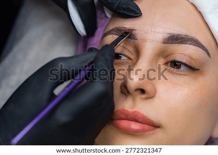 Close up of eyebrow shaping and mapping before permanent makeup, beautician marking brow symmetry in beauty salon