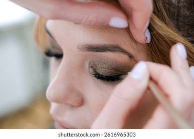 close up eyes Makeup, Make up in process , beautician applies makeup eyeshadows in bright professional studio, Beautiful woman face, Hand of master in beauty salon, wedding preparation