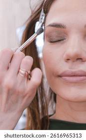 close up eyes Makeup, Make up in process , beautician applies makeup eyeshadows in bright professional studio, Beautiful woman face, Hand of master in beauty salon, wedding preparation