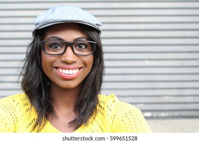 Close Face Of African Female With Glasses And Newspaper Boy Hat