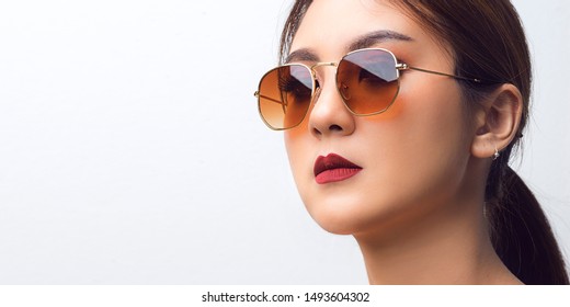 Close Up Face, Asian Woman Wearing Sunglasses In Studio White Background. Beautiful Girl Applying Cosmetic Lipstick Make Up Red Color On Mouth.