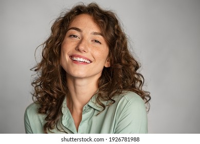 Close up face of beautiful young woman smiling and looking at camera isolated on grey background. Portrait of beauty natural girl with copy space. Female student in casual standing against gray wall.