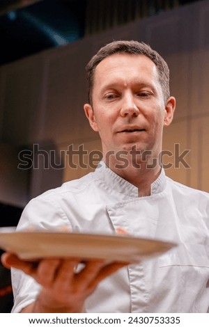 close up face the chef demonstrates a ready-made fish dish at arm's length in a professional kitchen