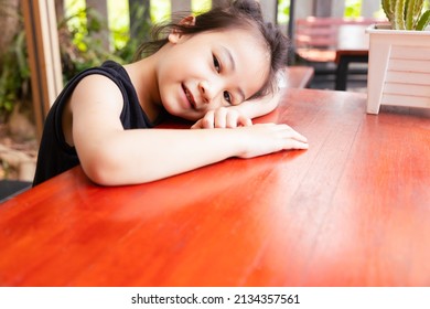 Close Up Face With Copy Space Of Adorable Asian Girl Kid Who Is Happily Sleeping Alone On The Table Outside Shows Concept Of Happy And Cheerful Emotion With Smiling And Relaxing.