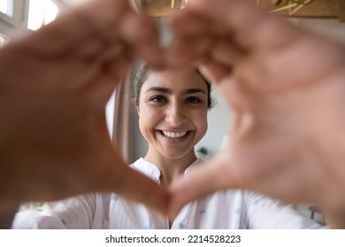 Close Up Face Of Happy Young 30s Indian Woman Smile Looks At Camera Joining Fingers Showing Symbol Of Love. Declaration Of Love, Female Shares Affection And Warmth To Beloved One. Donation, Feelings