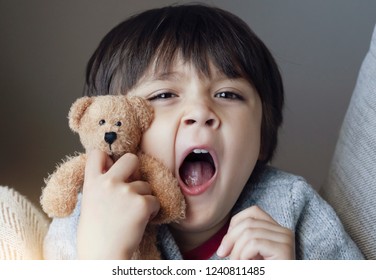 Close Up Face Of Kid Yawning And Holding Teddy Bear, Sleepy Child Yawning And Looking At Cameta, Head Shot Tired Child Get A Cold During Weather Change, Children Health Care Concept