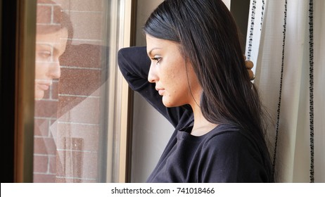 Close up of Face of a Pensive Pretty Depressed Young Woman, Looking Down by a Window, Worried or Sad.