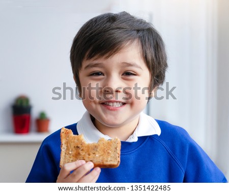 Close up face Preschool boy eating honey on toasted for his breakfast before go to school, Cropped shot Healthy child eating butter on bread in the morning, Healthy food for kid concept