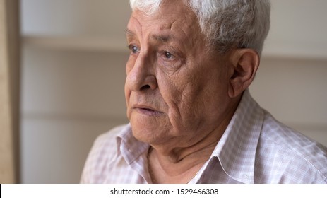 Close up face of sad caucasian senior 80s man feels upset and lonely standing indoors looking away, concept of solitude, nursing home care, senile diseases Parkinson Alzheimer Dementia ageing process - Powered by Shutterstock