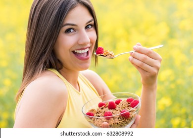 Close Up Face Shot Of Attractive Young Woman Eating Healthy Crispy Whole Grain Cereal Breakfast Outdoors.