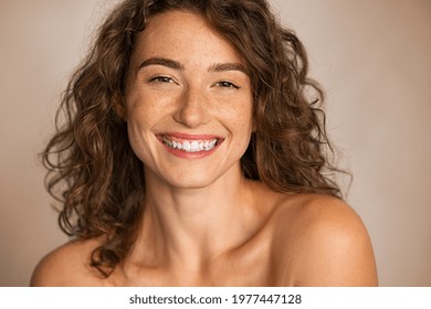 Close up face of smiling woman with wavy hair looking at camera isolated. Happy beauty woman feeling good after skin treatment. Portrait of curly hair girl smiling and feeling fresh after spa.