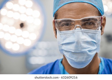 Close Up Face Of Surgeon Man Looking At Camera With Protective Mask. Dental Assistant With Surgical Mask And Safety Glasses In Dental Clinic. Happy Successful Surgeon In A Operating Room.