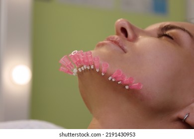 Close up face of thread lifting procedure. Professional cosmetologist in pink medical gloves inserting needles in chin scin. Anti-aging treatment and face lift in cosmetology clinic. Pretty woman fac
