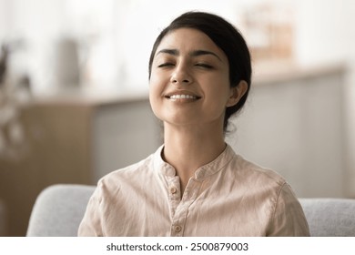 Close up face of young pretty Indian woman do meditation practice, breathing fresh air with eyes closed, feel serenity and inner happiness. Mental well-being, stress reduction, and spiritual growth - Powered by Shutterstock