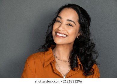 Nahaufnahme der jungen Frau mit schönem Lächeln einzeln auf grauer Wand mit Kopienraum. Erfolgreiches multiethnisches Mädchen. Latino-Frau, die eine Kamera auf graue Wand mit einem großen weißenden Zähnen anschaut.